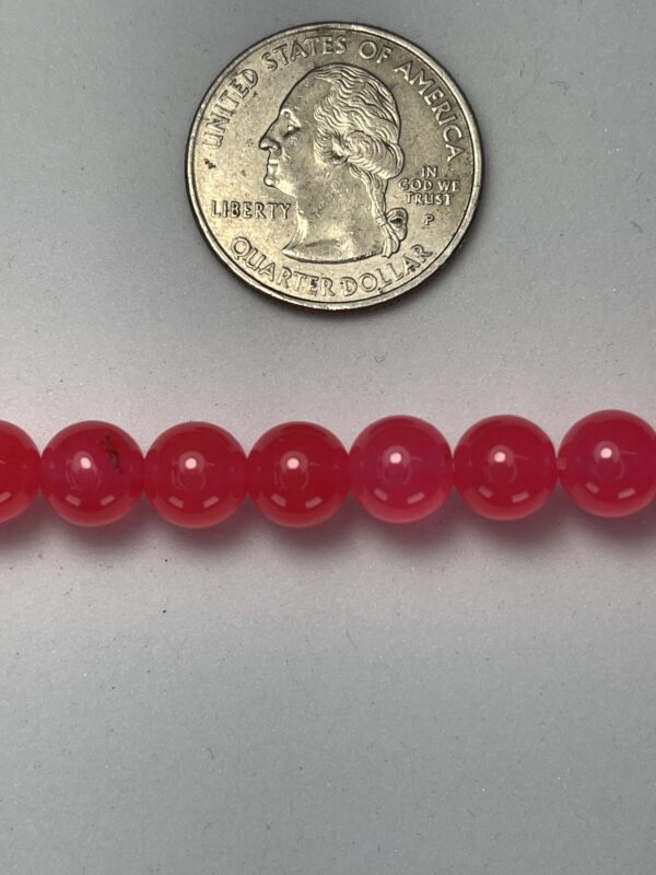Pink round beads with quarter for scale.