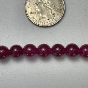 Here's an alt tag for the image: Dark purple beads with quarter for scale.
