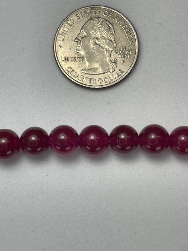 Here's an alt tag for the image: Dark purple beads with quarter for scale.