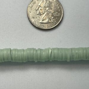 Quarter coin next to green bead string.