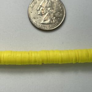 Yellow beads beside a US quarter coin.